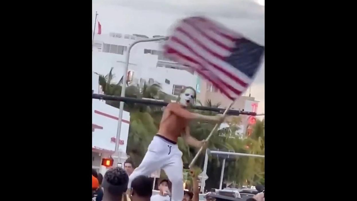 Joker Declares End of Pandemic While Standing on Car, Waving Flag, Making It Rain Cash