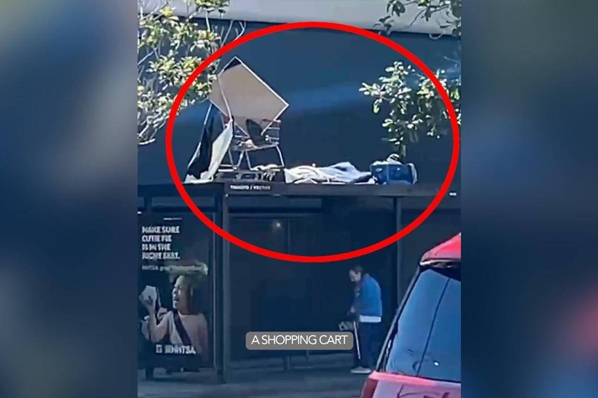 Homeless Man Creates Makeshift Sleeping Encampment On Top Of Bus Stop With A Shopping Cart