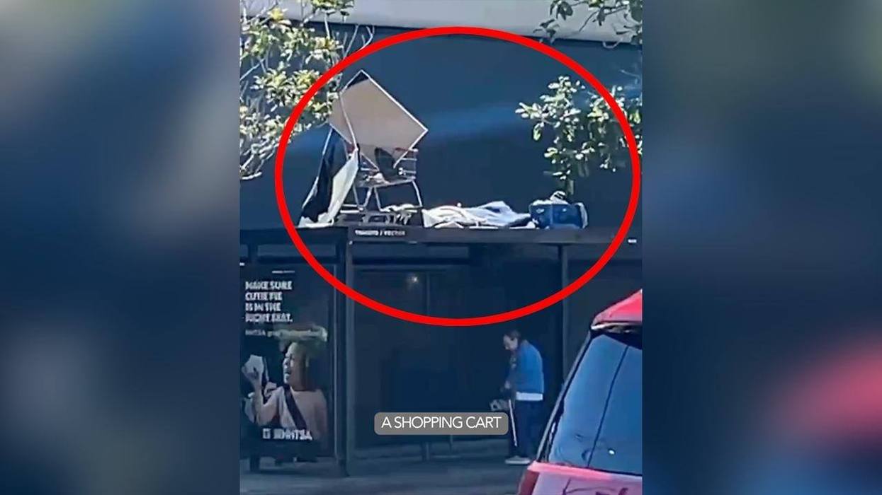 Homeless Man Creates Makeshift Sleeping Encampment On Top Of Bus Stop With A Shopping Cart
