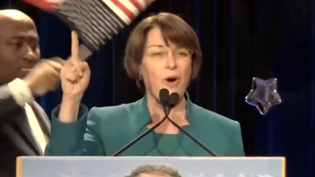 Amy Klobuchar brags about helping Somalis send your tax dollars to Somalia…in front of upside down American flag